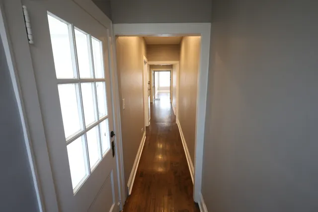 a view of a hallway with wooden floor and stairs