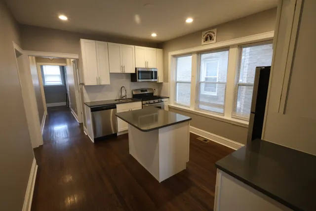 a kitchen with kitchen island granite countertop a sink appliances and cabinets