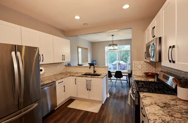 a kitchen with stainless steel appliances granite countertop a refrigerator a stove and a wooden floors