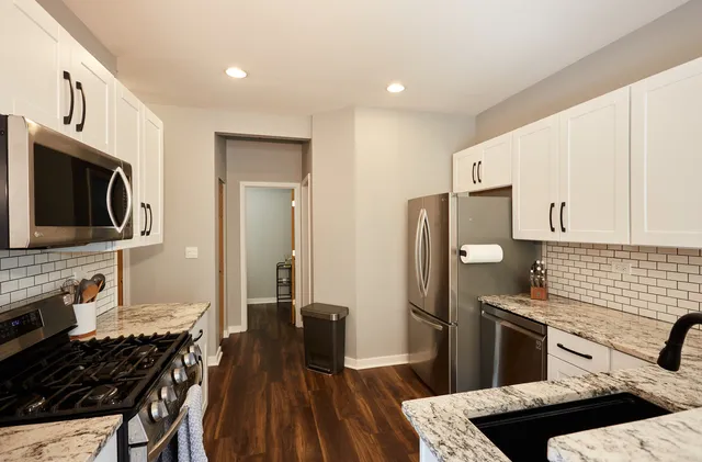 a kitchen with stainless steel appliances a kitchen island hardwood floor sink stove and refrigerator