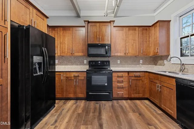 a kitchen with granite countertop a refrigerator stove top oven and sink
