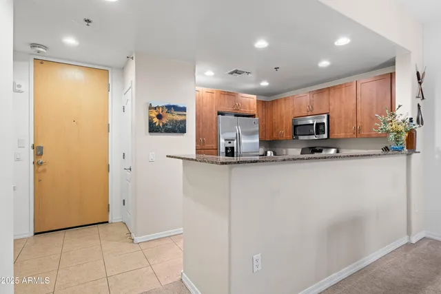 a view of kitchen with stainless steel appliances granite countertop a refrigerator and a stove top oven