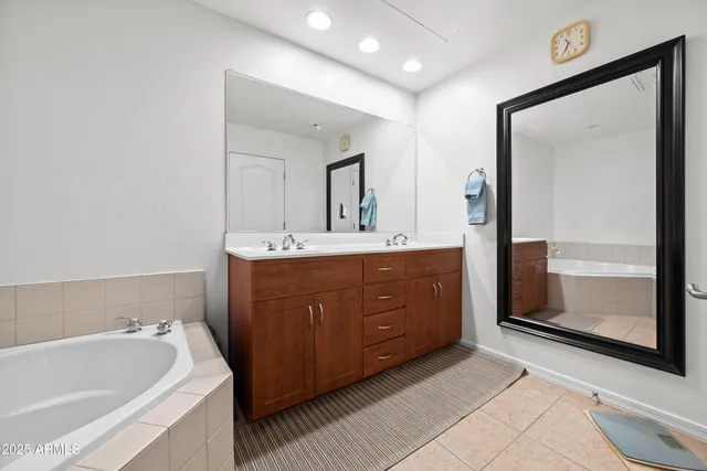 a spacious bathroom with a tub sink and mirror
