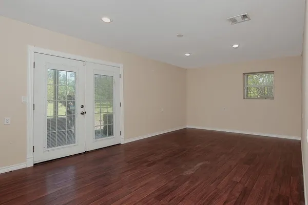 a view of an empty room with wooden floor and a window