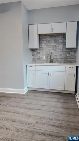 a kitchen with granite countertop a sink cabinets and wooden floor