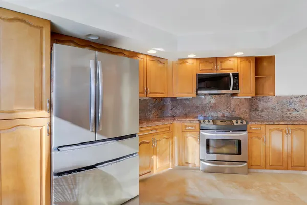 a kitchen with stainless steel appliances granite countertop a refrigerator a stove and a sink with large window