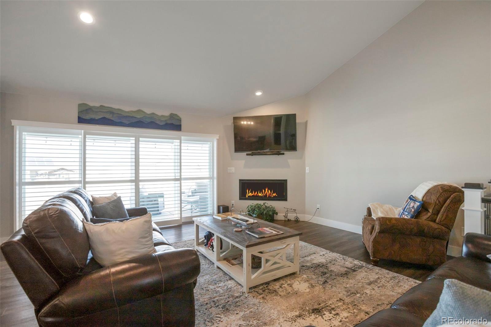 3711 Harrier Hawk Road Dacono, CO 80514 - Photo 11 of 40 a living room with furniture a flat screen tv and a fireplace