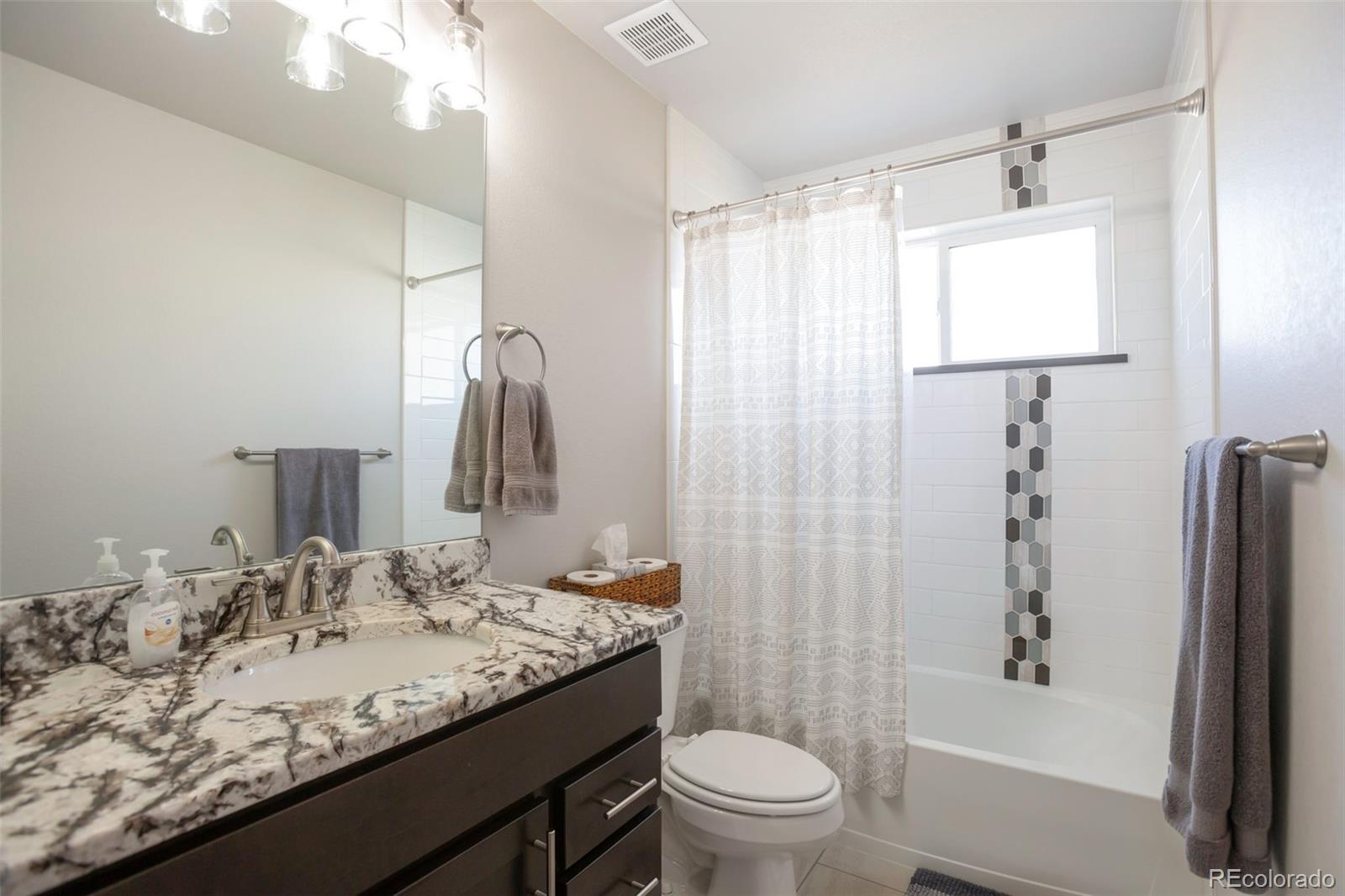 3711 Harrier Hawk Road Dacono, CO 80514 - Photo 23 of 40 a bathroom with a granite countertop sink toilet and shower