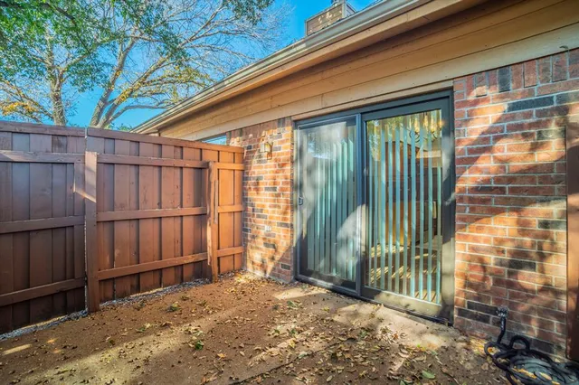 a view of a backyard with wooden fence and large trees