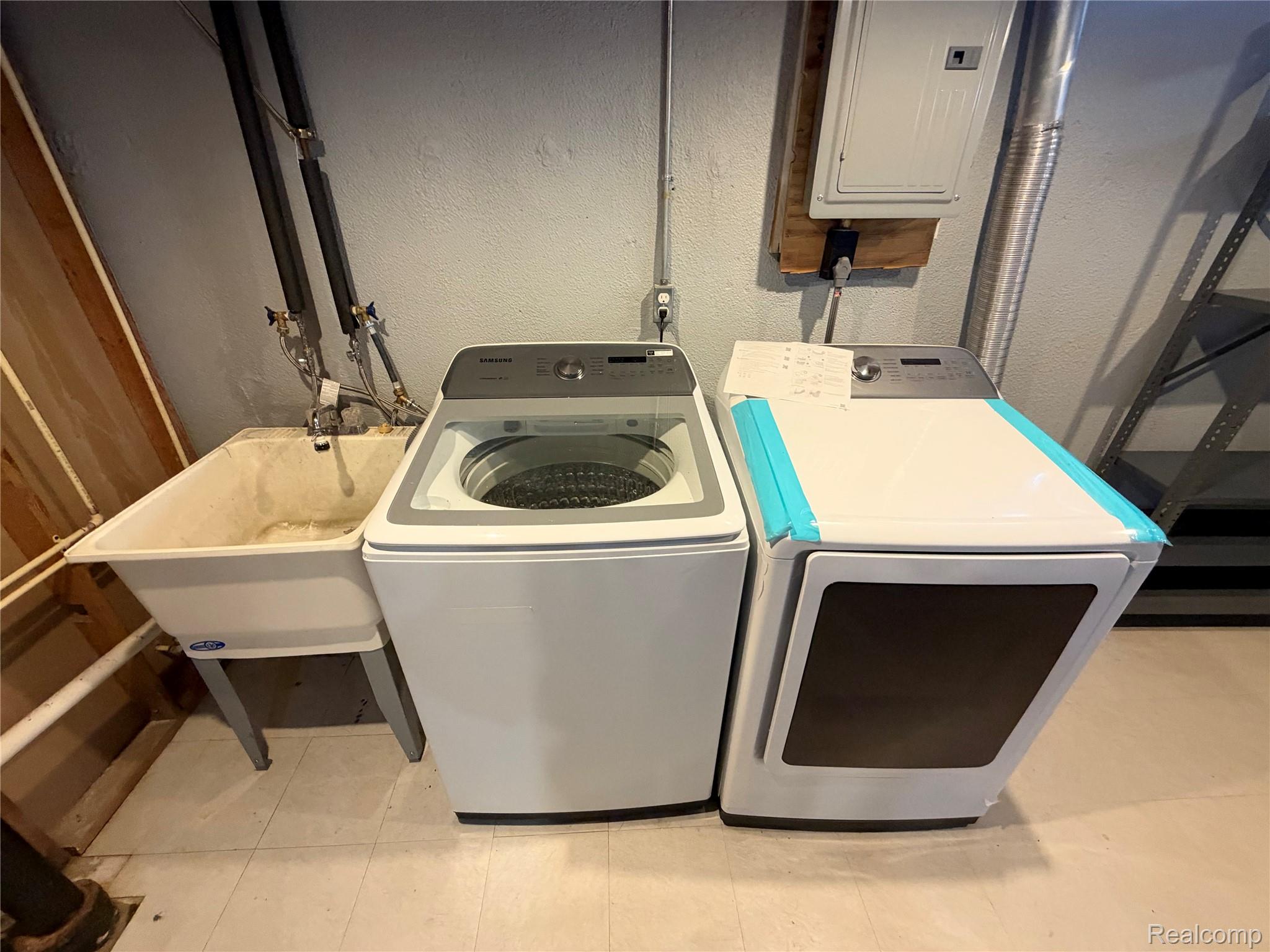 14629 Newburgh Road Livonia, MI 48154 - Photo 19 of 27 Utility sink with a wall-mounted faucet, accompanied by a top-loading washing machine and a front-loading dryer