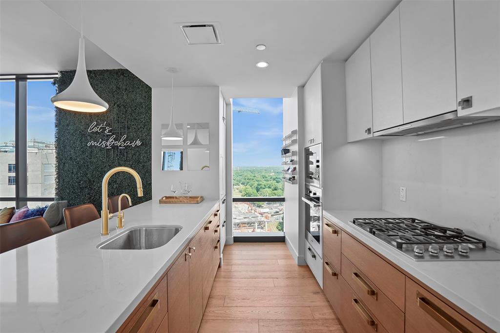 70 Rainey Street, Unit 1409 Austin, TX 78701 - Photo 3 of 38 Kitchen with light stone counters, expansive windows, stainless steel appliances, light wood-style floors, and hanging light fixtures
