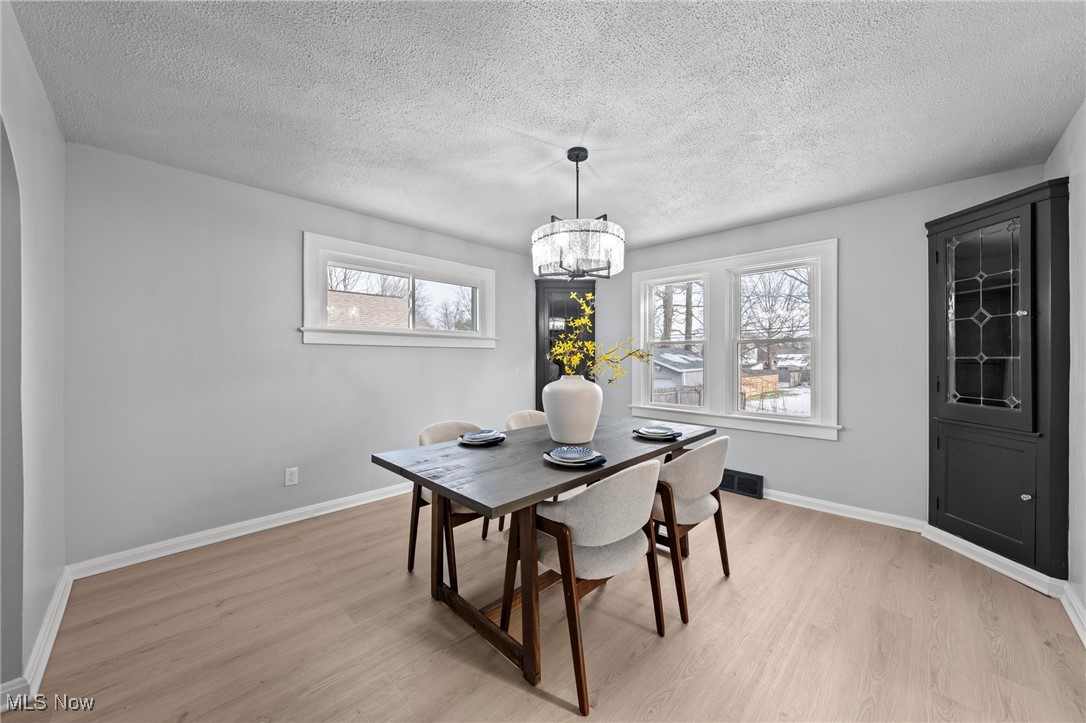 1193 Mayfield Ridge Road Cleveland, OH 44124 - Photo 12 of 35 Dining space with a textured ceiling, light wood-style flooring, plenty of natural light, and a chandelier