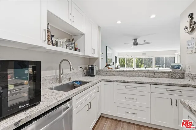 a kitchen with granite countertop white cabinets and stainless steel appliances