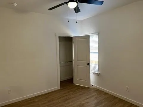an empty room with wooden floor cabinet and windows