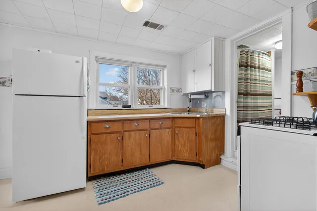 a kitchen with granite countertop a refrigerator a sink a stove and white cabinets