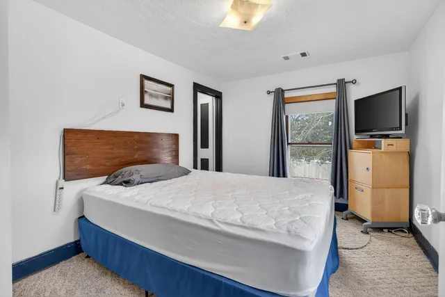 a bedroom with a bed and painting on the wall