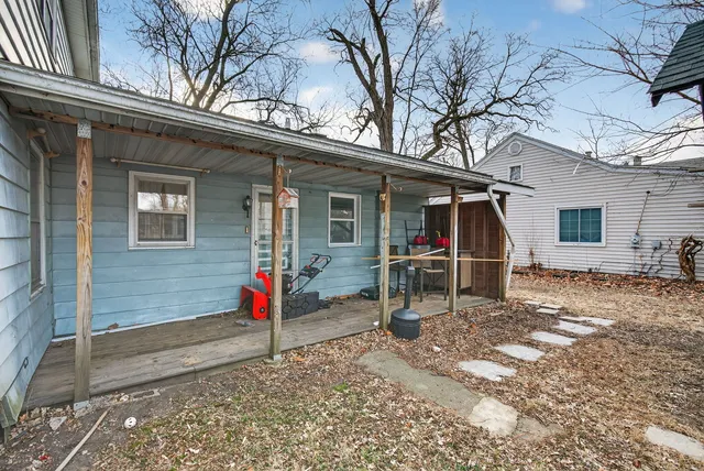 a view of a porch with wooden chairs and floor to ceiling window