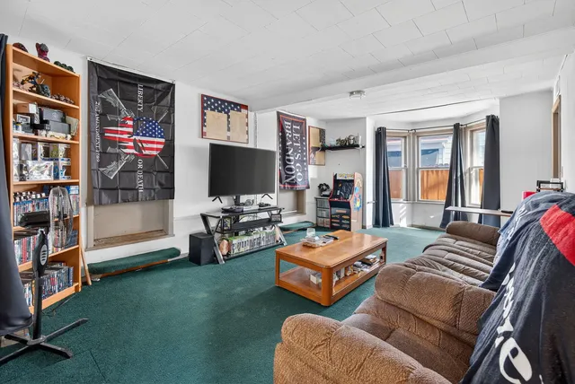 a living room with furniture a bookshelf and a window