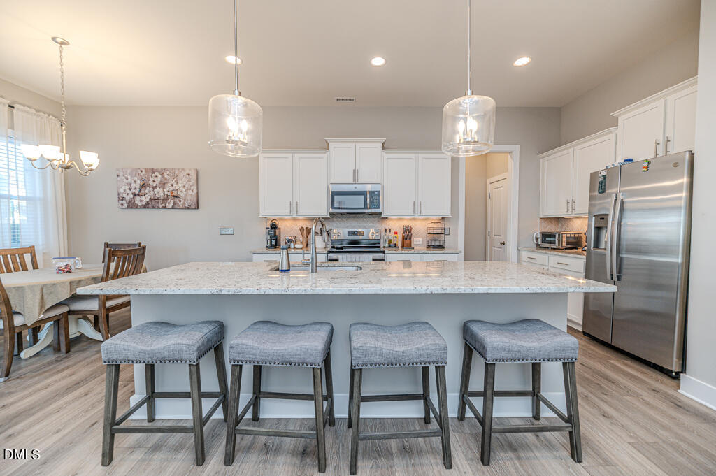 22 Camille Brooks Drive Angier, NC 27501 - Photo 29 of 52 a kitchen with a dining table chairs refrigerator and microwave