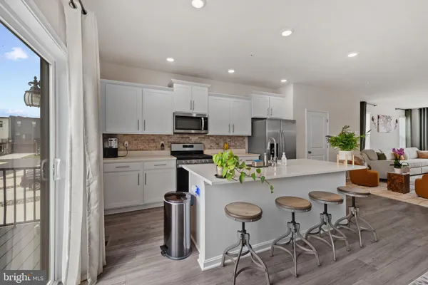 a kitchen with stainless steel appliances granite countertop a table chairs and a refrigerator