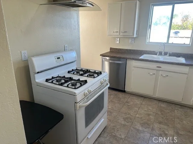 a white kitchen with a stove a sink and a window