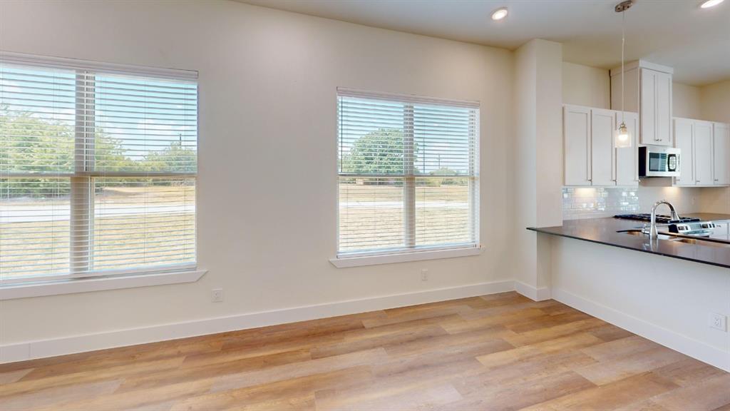 373 Buck Ridge Drive Frisco, TX 75068 - Photo 8 of 24 Wood-finish flooring throughout, bright recessed lighting, white cabinetry with under-cabinet lighting, stainless steel appliances, and dark stone countertops