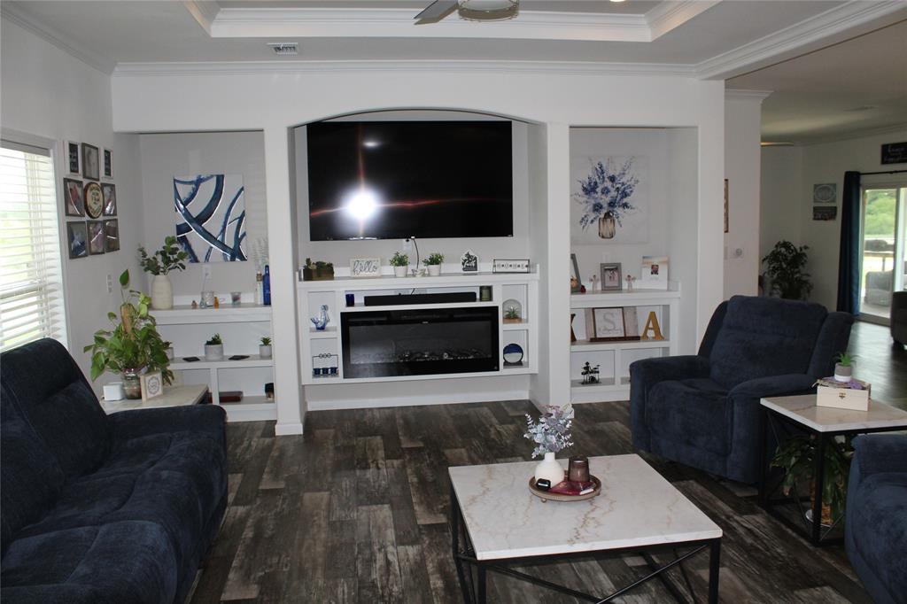 2077 A Shawver Road Perrin, TX 76486 - Photo 4 of 35 Living area featuring wood-finish flooring, a tray ceiling with a ceiling fan, and a built-in media center with an electric fireplace