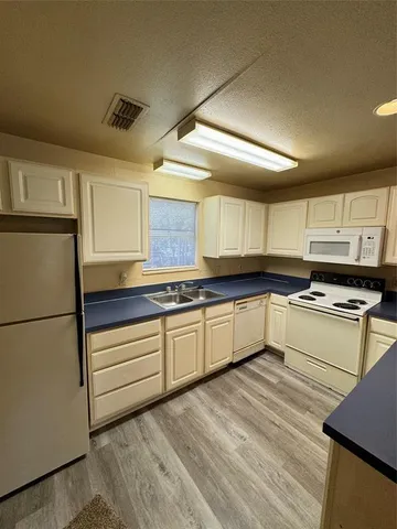 a kitchen with granite countertop a sink cabinets stainless steel appliances and a window