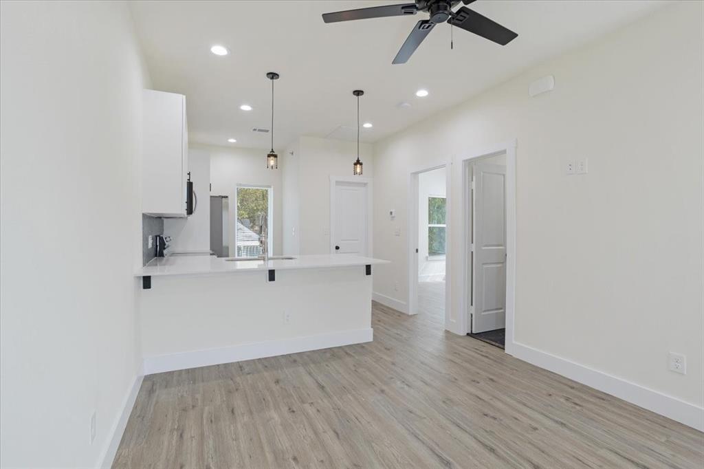 515 South 1st Street Sherman, TX 75090 - Photo 1 of 1 Kitchen with a wealth of natural light, white cabinetry, light wood-style floors, and a peninsula