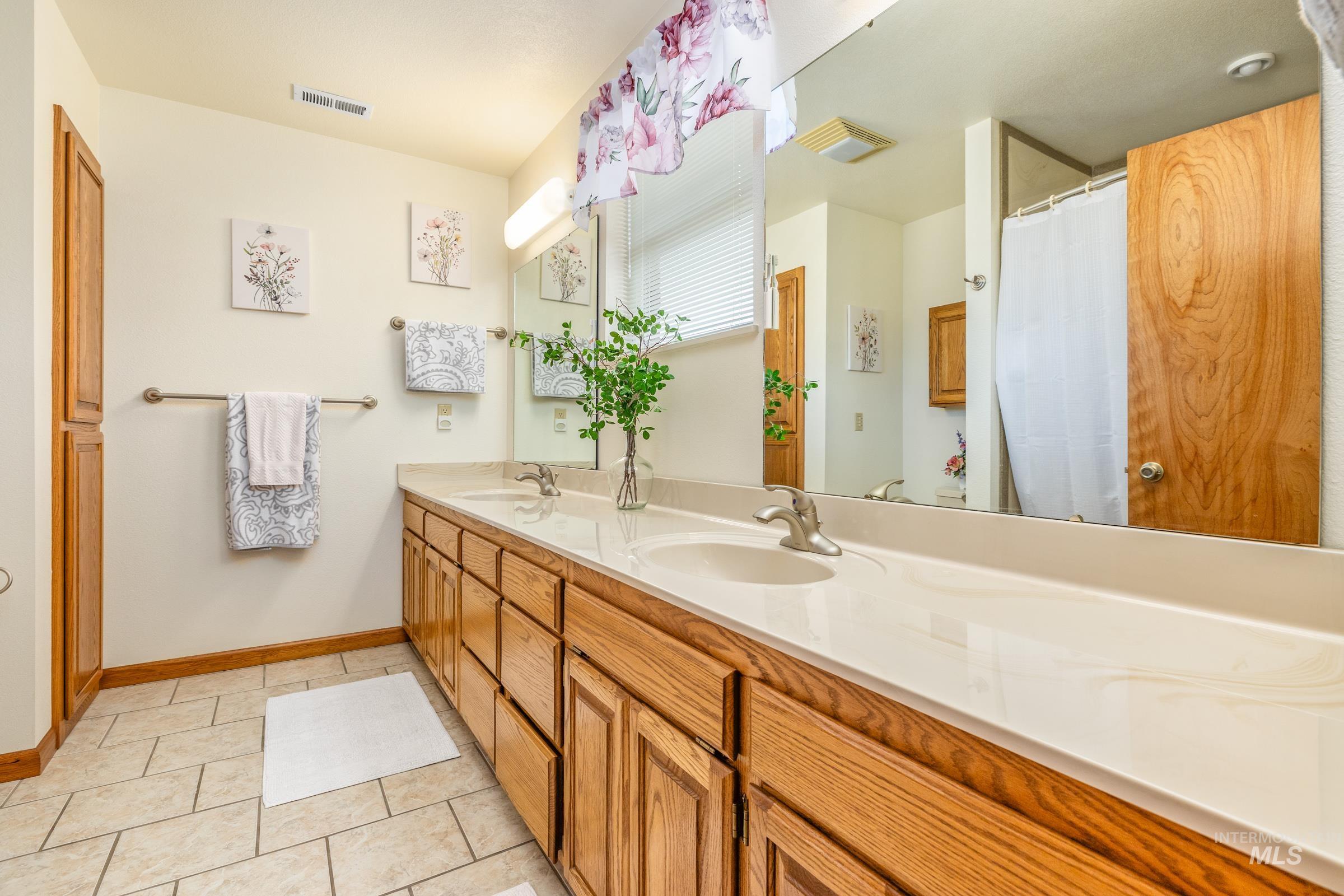 10514 Airpark Loop Road Melba, ID 83641 - Photo 13 of 47 Bathroom featuring double vanity, a shower with shower curtain, and light tile patterned floors