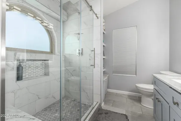 a bathroom with a granite countertop bathtub shower sink vanity and toilet