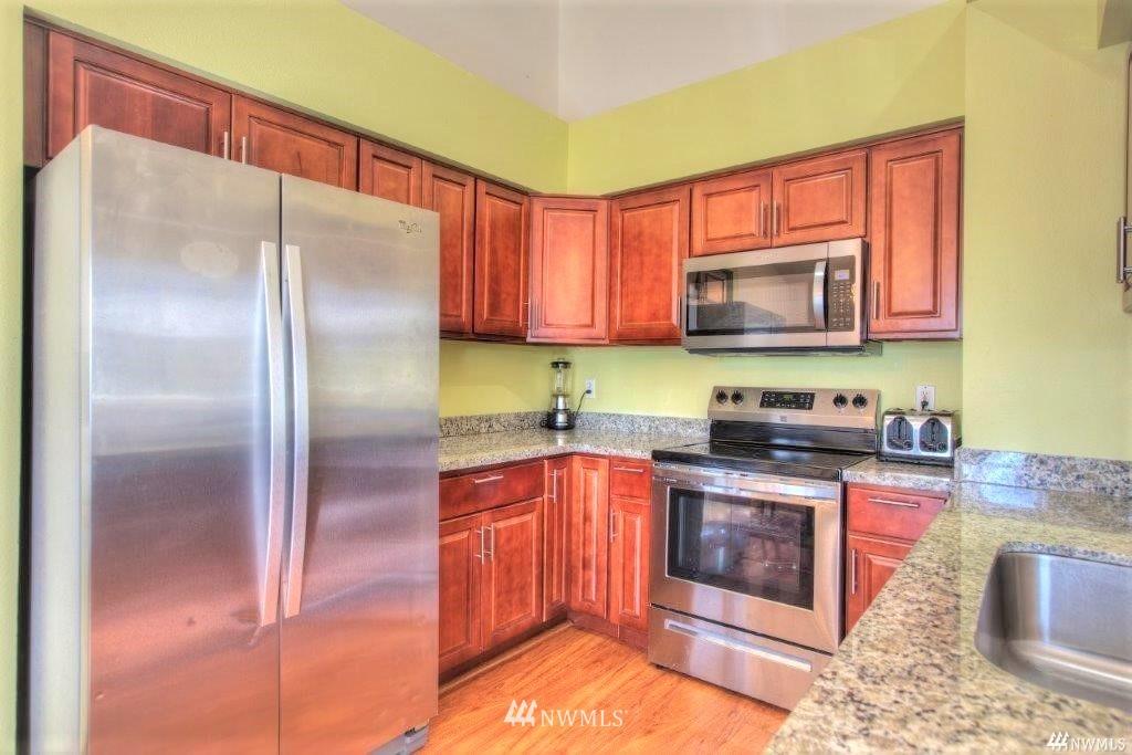 833 Southwest Sunset Boulevard, Unit E22 Renton, WA 98057 - Photo 3 of 18 a kitchen with stainless steel appliances granite countertop a stove a sink and a microwave