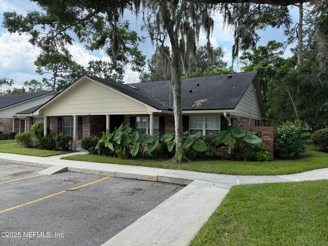 a front view of a house with a yard and potted plants