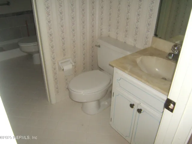 a bathroom with a granite countertop toilet and a sink