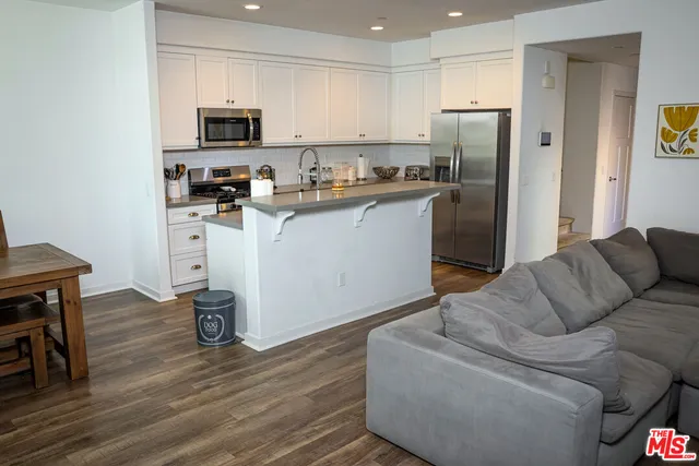 a living room with stainless steel appliances a refrigerator a stove a microwave a sink and a cabinets