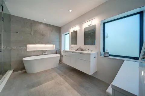 a bathroom with a double vanity sink mirror and bathtub