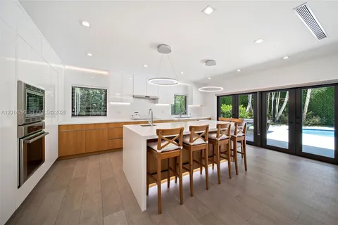 a kitchen with stainless steel appliances granite countertop wooden floor a large window and a kitchen island