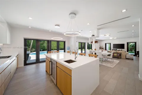 a kitchen with counter top space a sink stove and living room view