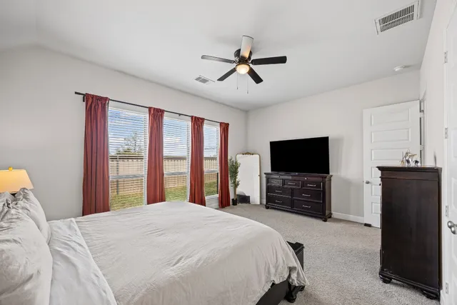a bedroom with a bed and a flat tv screen on dresser