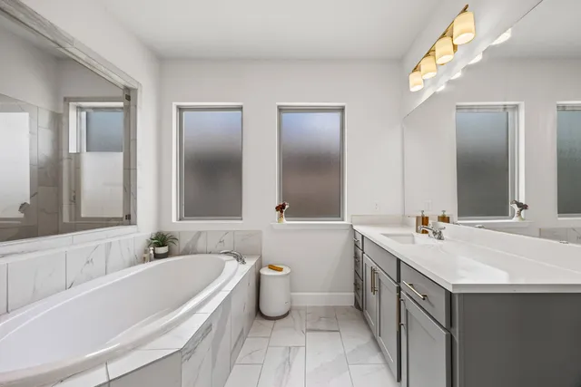 a bathroom with a tub a sink shower and mirror