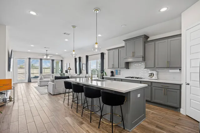 a kitchen with sink stove and white cabinets with wooden floor