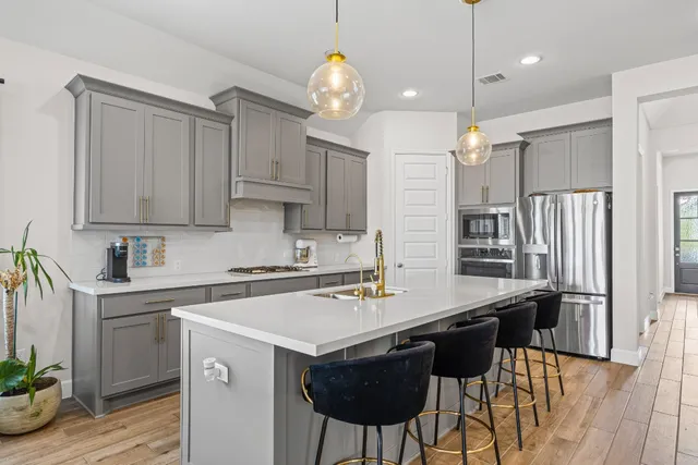 a kitchen with stainless steel appliances a stove a sink a refrigerator a center island a table and chairs