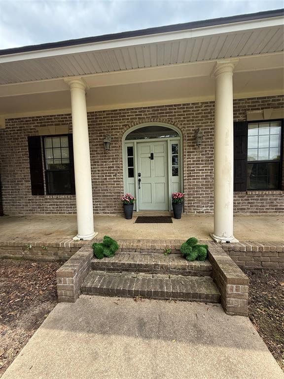 201 Woodhaven Drive Minden, LA 71055 - Photo 2 of 31 Brick facade featuring a covered porch with large round columns, an arched entry, and a light-colored front door