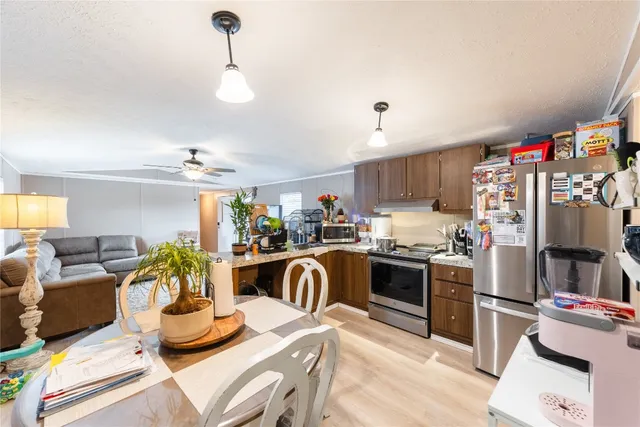 a kitchen with stainless steel appliances granite countertop a sink dishwasher a stove and a refrigerator with wooden floor