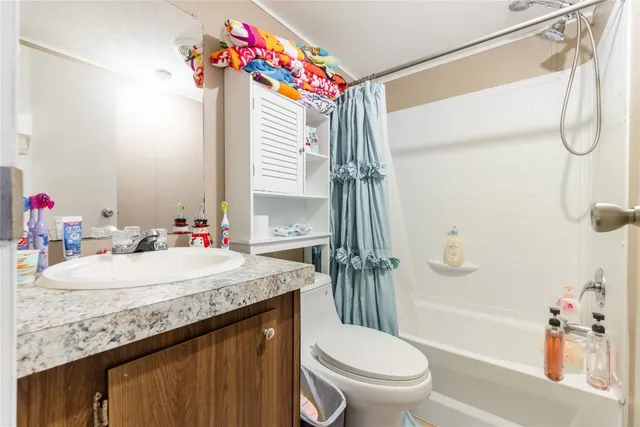 a bathroom with a granite countertop sink a toilet and shower