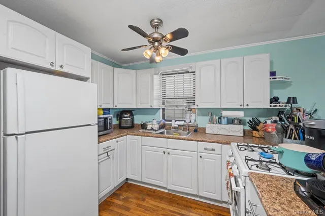 a kitchen with a refrigerator a sink cabinets and wooden floor
