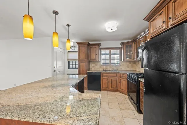 a kitchen with stainless steel appliances granite countertop a sink a stove a refrigerator a washer dryer and a dining table