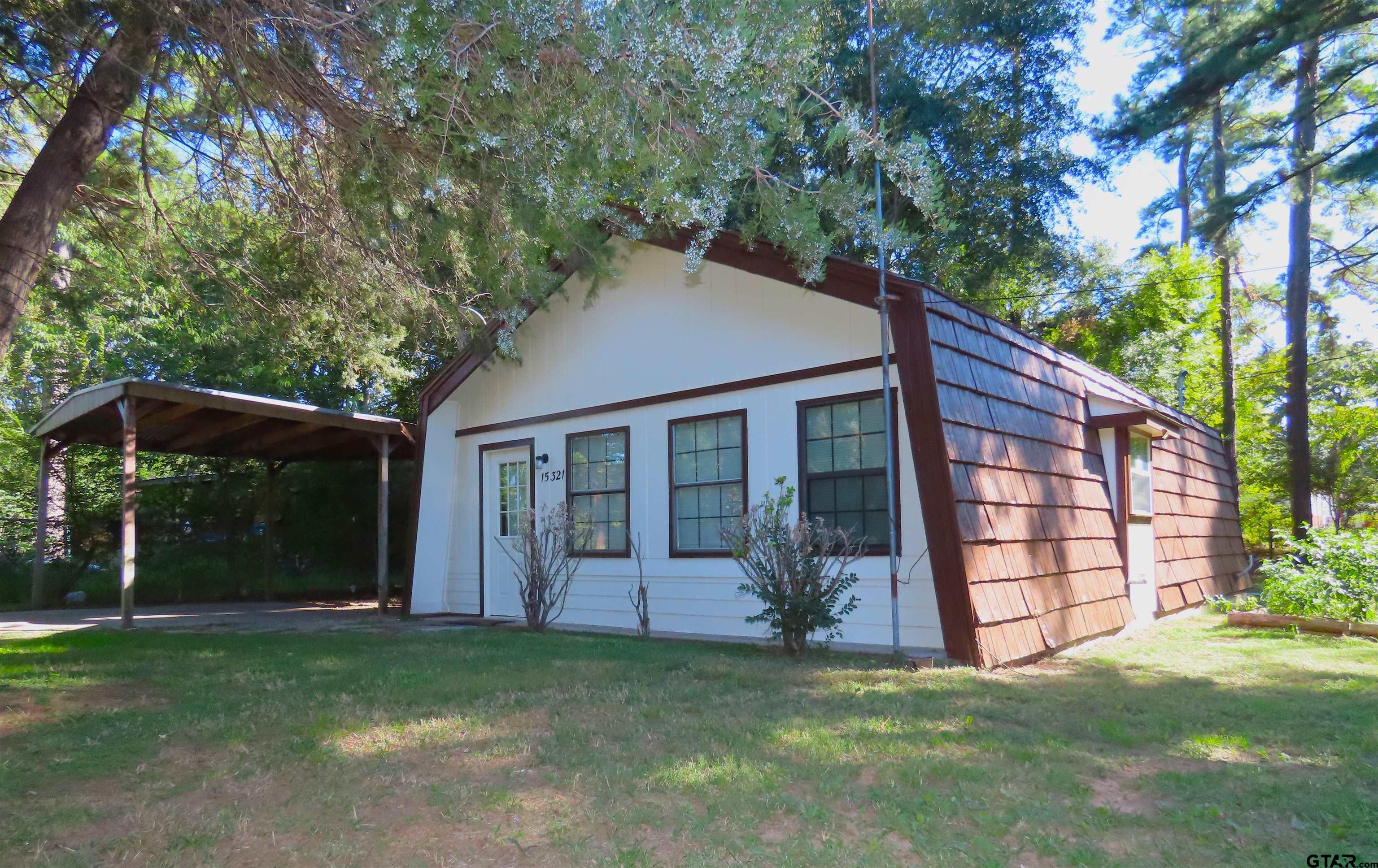 a view of a house with a yard and a large tree