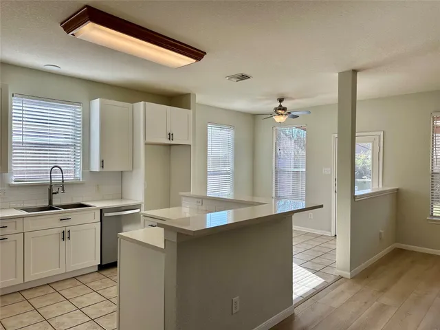 a kitchen with a sink dishwasher a stove and white cabinets with wooden floor