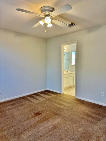 an empty room with a chandelier fan and windows